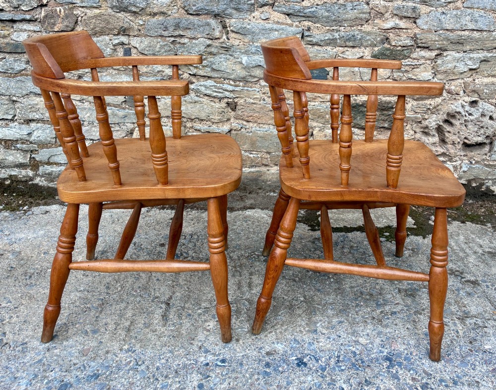 A pair of antique wooden captains chairs with contoured elm seats, turned spindles, rounded armrests, and turned legs. View VII