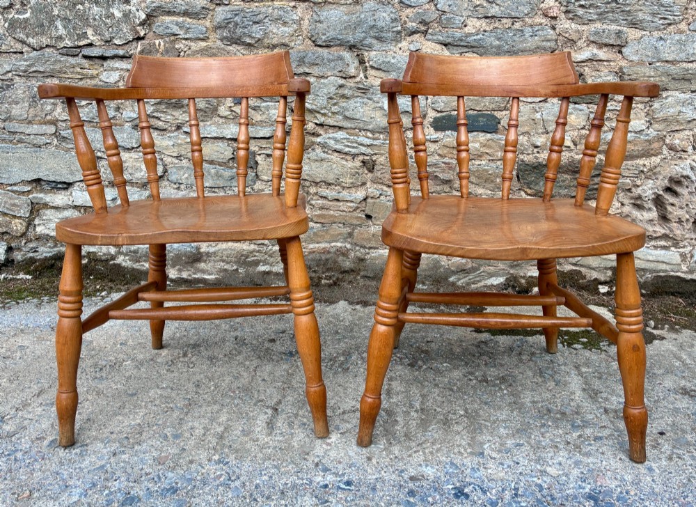 A pair of antique wooden captains chairs with contoured elm seats, turned spindles, rounded armrests, and turned legs. View VIII