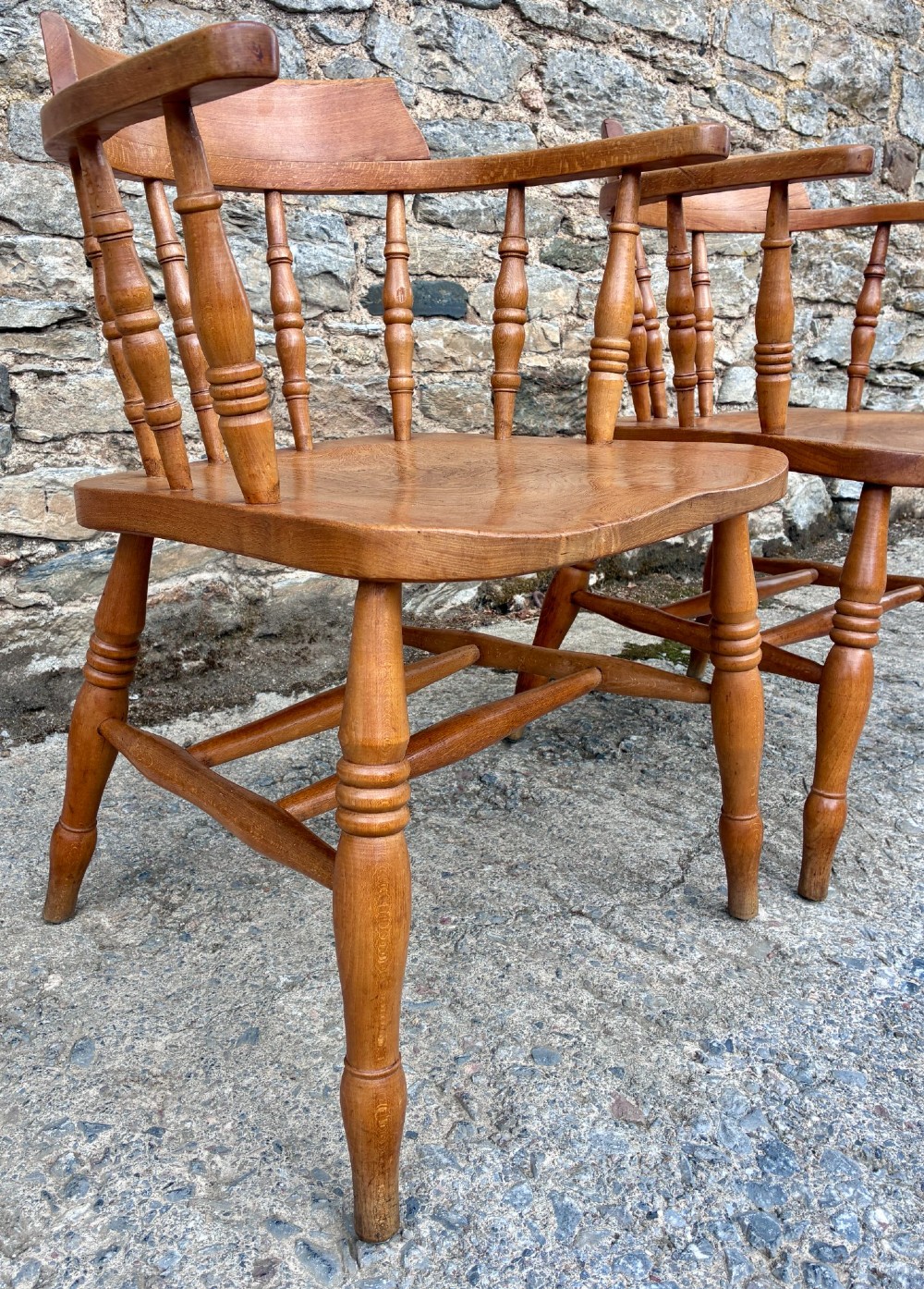 A pair of antique wooden captains chairs with contoured elm seats, turned spindles, rounded armrests, and turned legs. View IX