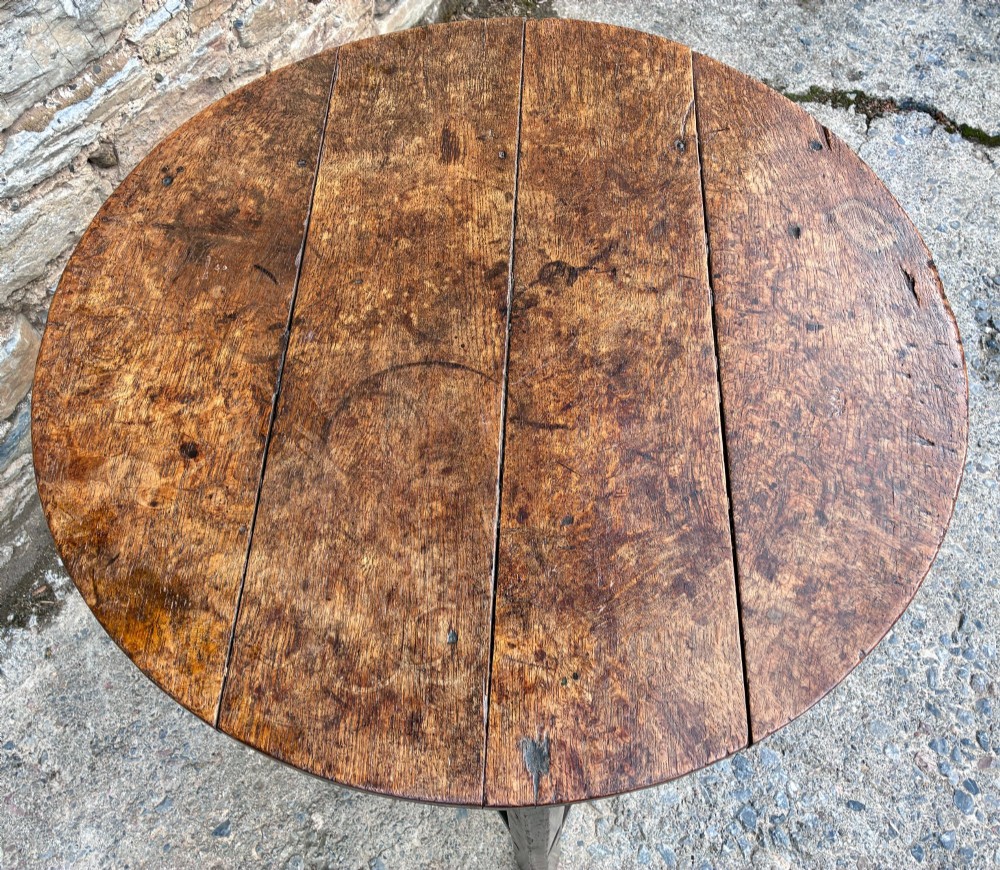An antique Georgian dark oak cricket table featuring a circular planked top resting on three straight legs with a lower triangular shelf. View XII