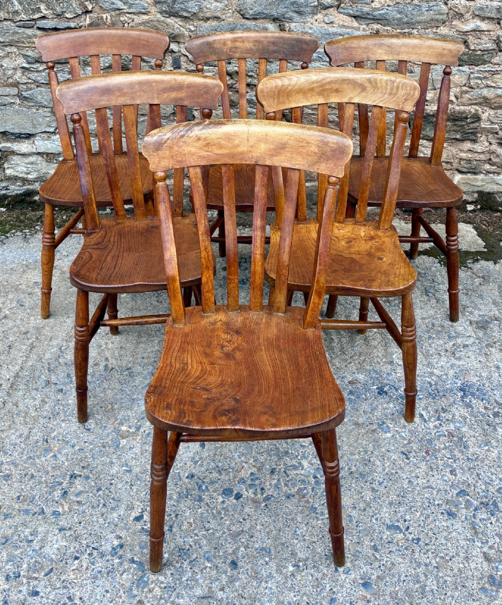 A set of six Victorian country dining chairs featuring curved top rails, vertical lathe back slats, shaped solid elm seats, and turned legs.