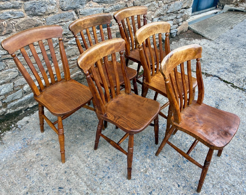 A set of six Victorian country dining chairs featuring curved top rails, vertical lathe back slats, shaped solid elm seats, and turned legs. View II