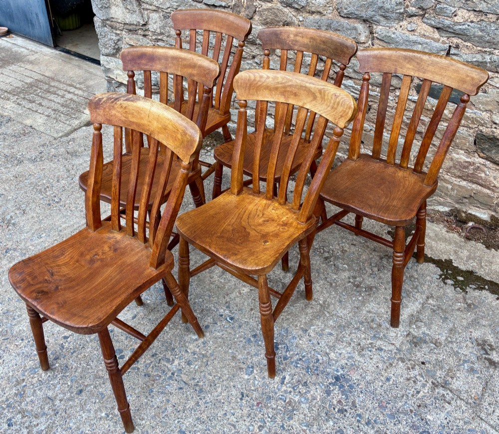 A set of six Victorian country dining chairs featuring curved top rails, vertical lathe back slats, shaped solid elm seats, and turned legs. View III