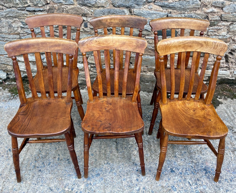 A set of six Victorian country dining chairs featuring curved top rails, vertical lathe back slats, shaped solid elm seats, and turned legs. View IV