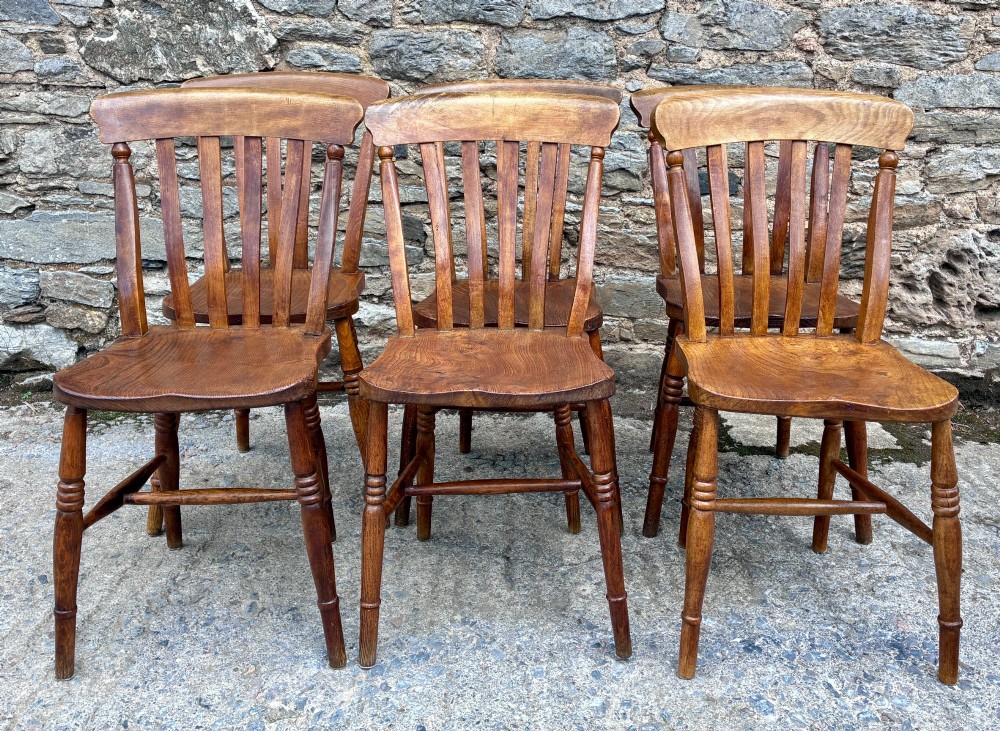 A set of six Victorian country dining chairs featuring curved top rails, vertical lathe back slats, shaped solid elm seats, and turned legs. View V