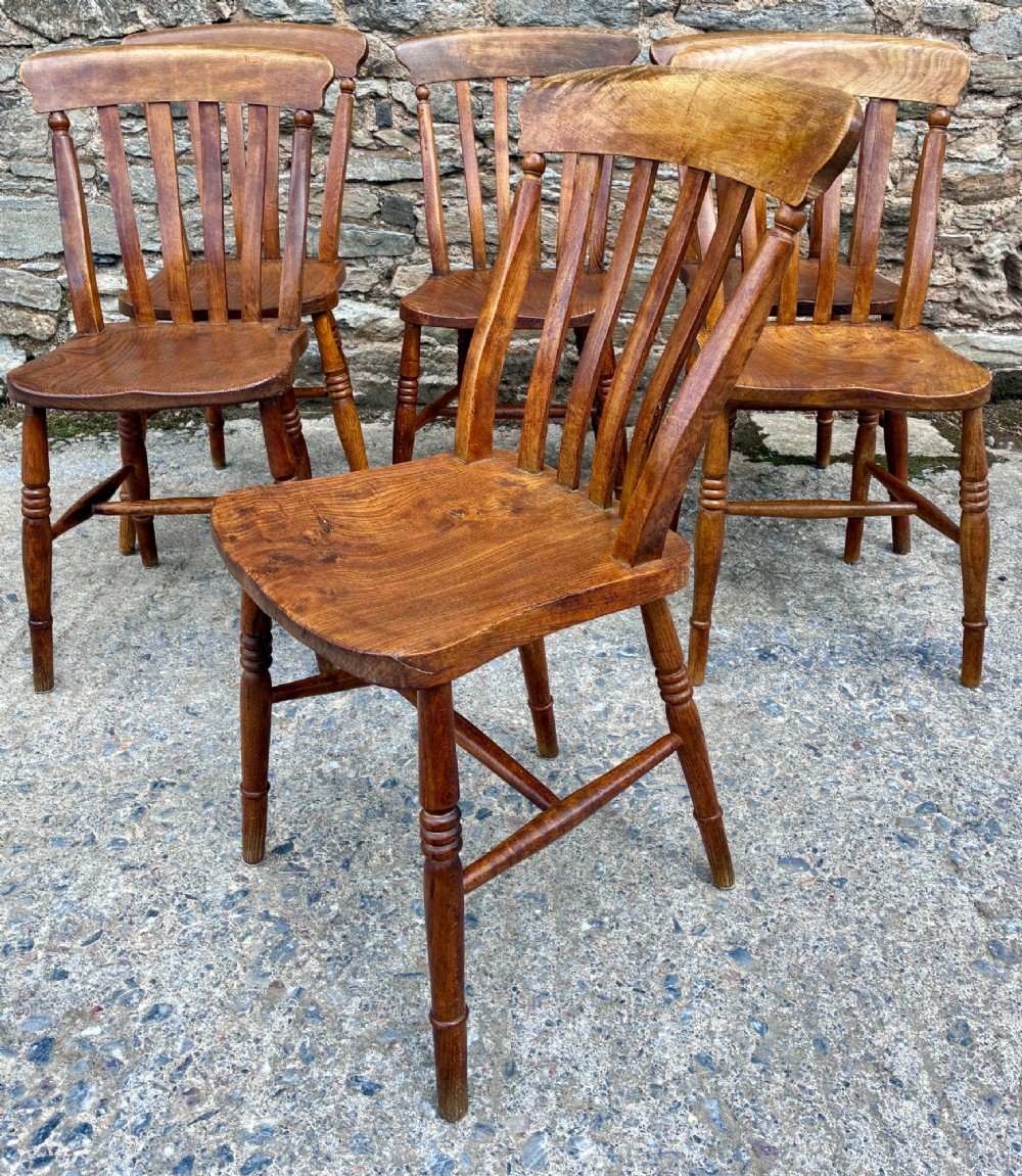A set of six Victorian country dining chairs featuring curved top rails, vertical lathe back slats, shaped solid elm seats, and turned legs. View VI