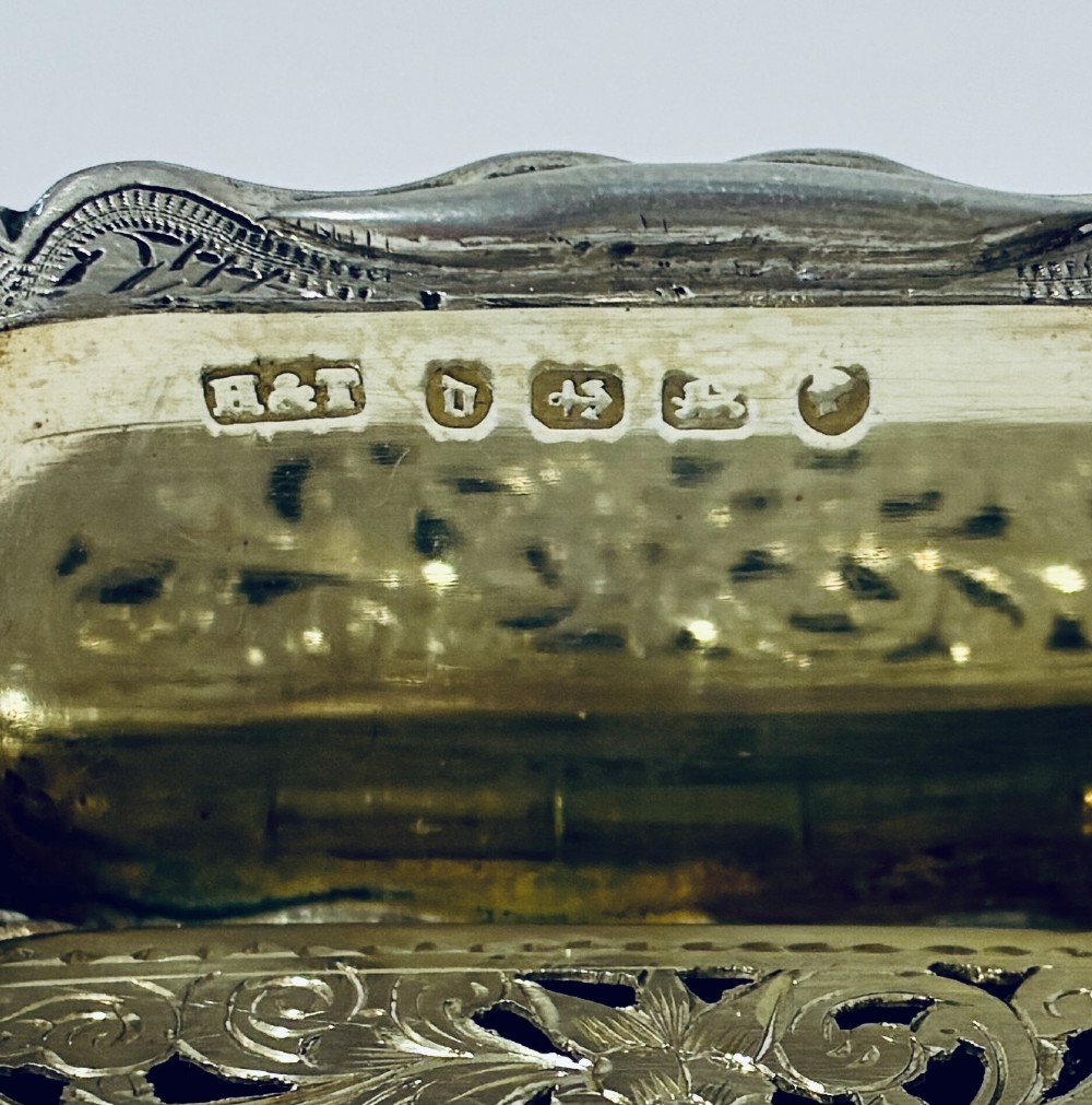 A small rectangular Victorian sterling silver vinaigrette featuring hand-engraved floral motifs, a central monogrammed cartouche, scalloped edges, and a side suspension ring. View IX
