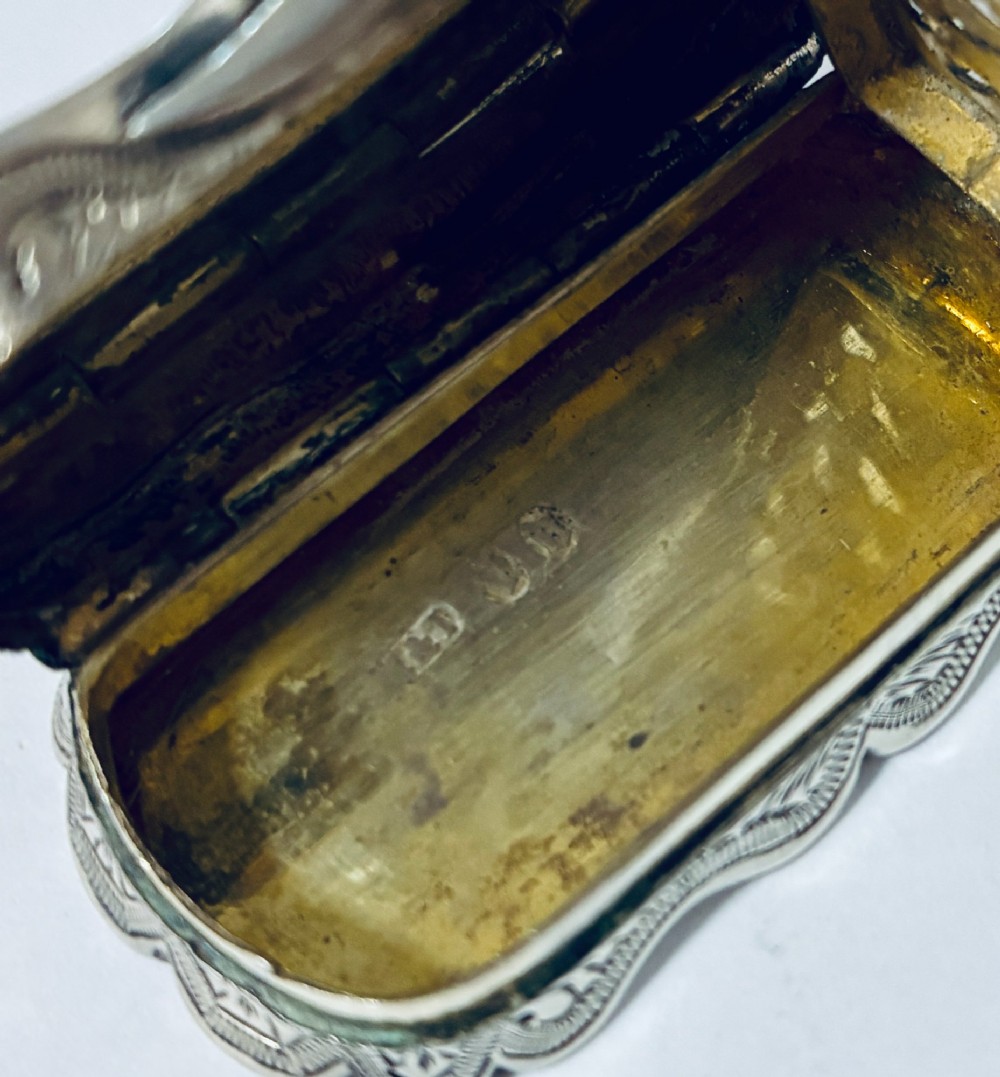 A small rectangular Victorian sterling silver vinaigrette featuring hand-engraved floral motifs, a central monogrammed cartouche, scalloped edges, and a side suspension ring. View XII