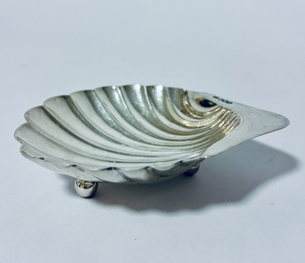 A sterling silver shell-shaped butter dish featuring fluted grooves and visible maker hallmarks on the top rim. View II