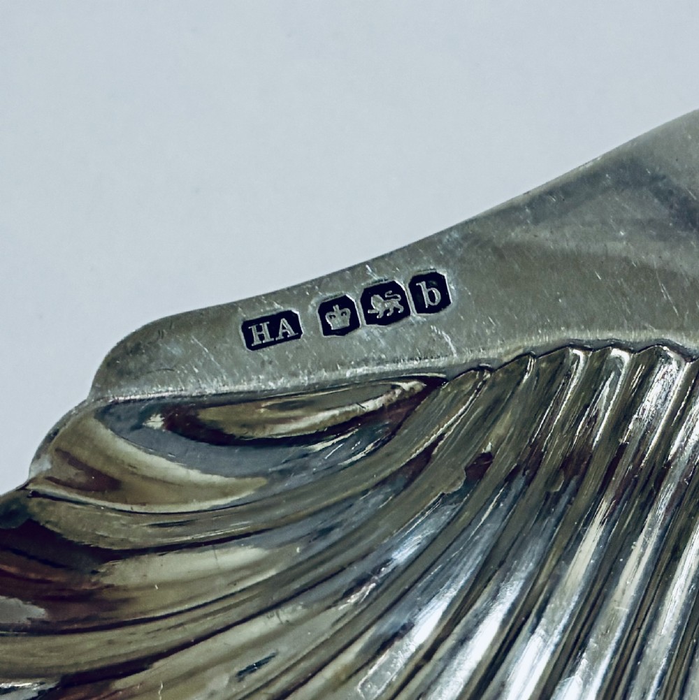 A sterling silver shell-shaped butter dish featuring fluted grooves and visible maker hallmarks on the top rim. View IV