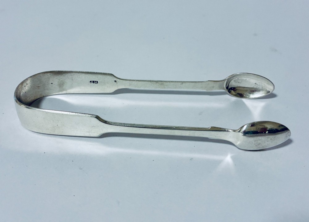 A pair of plain polished sterling silver sugar tongs with spoon-shaped grips and assay hallmarks stamped along the inner curve. View III