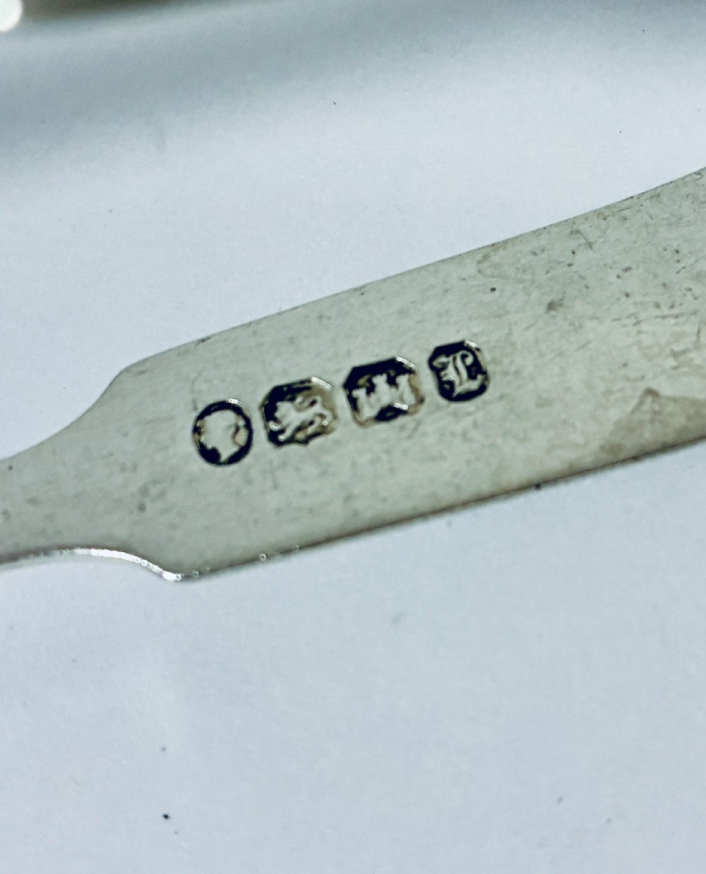 A pair of plain polished sterling silver sugar tongs with spoon-shaped grips and assay hallmarks stamped along the inner curve. View IV