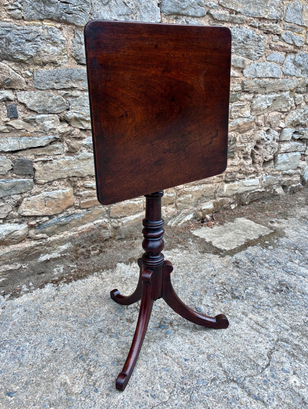 A Regency era dark mahogany tilt-top wine table featuring a rectangular surface, turned central pedestal stem, and a splayed tripod base. View XI