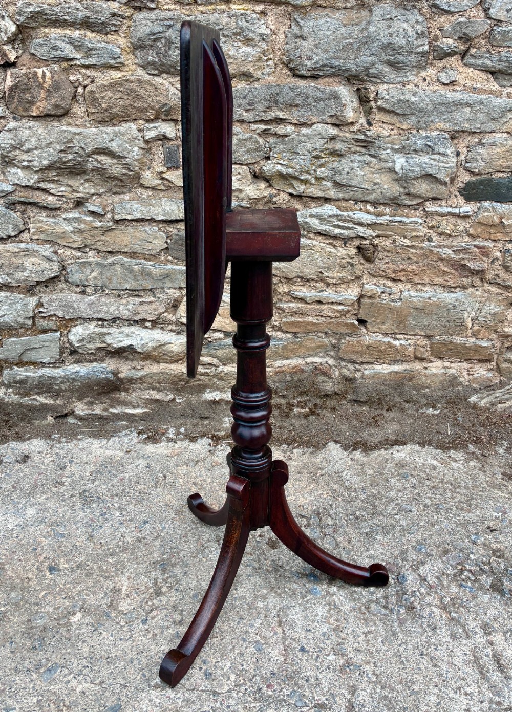 A Regency era dark mahogany tilt-top wine table featuring a rectangular surface, turned central pedestal stem, and a splayed tripod base. View XII