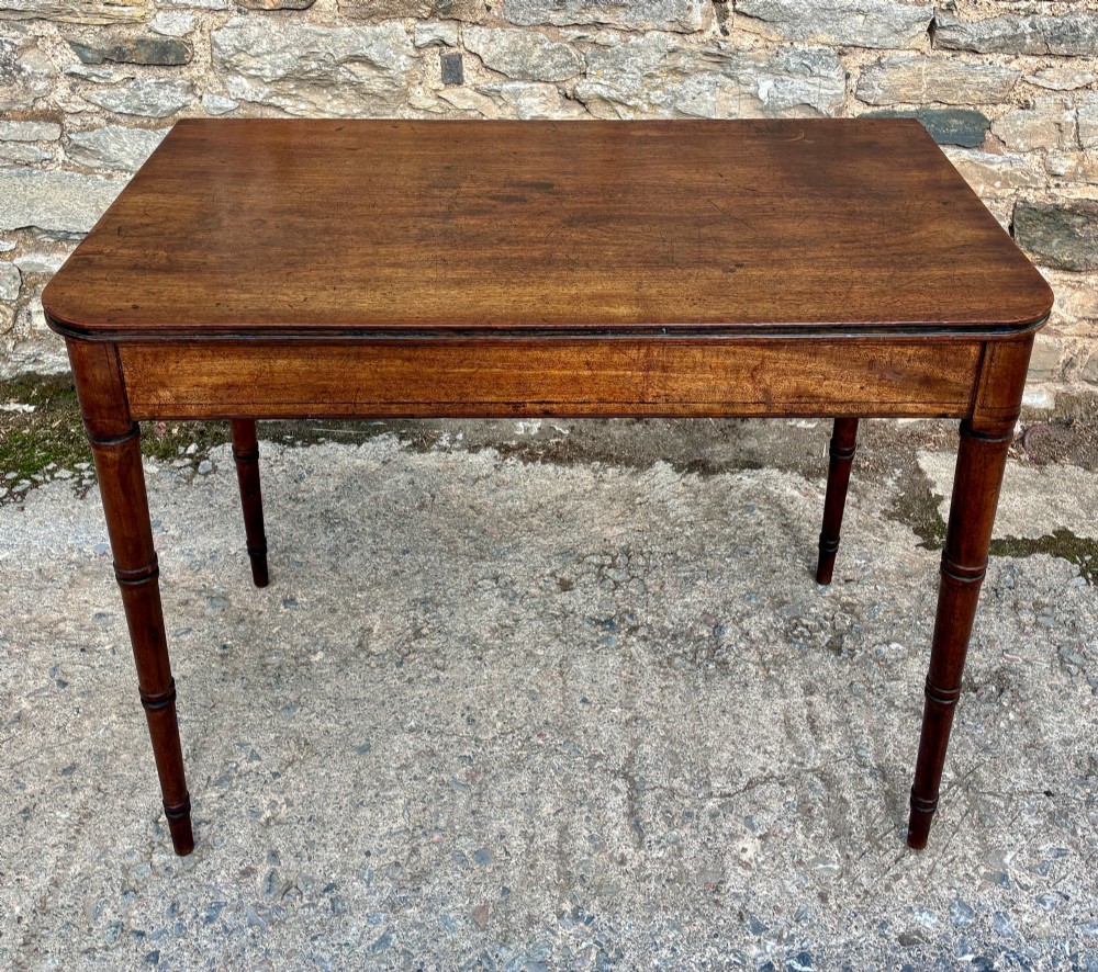A rectangular Georgian mahogany side table featuring rounded top corners and four ring-turned tapered legs.