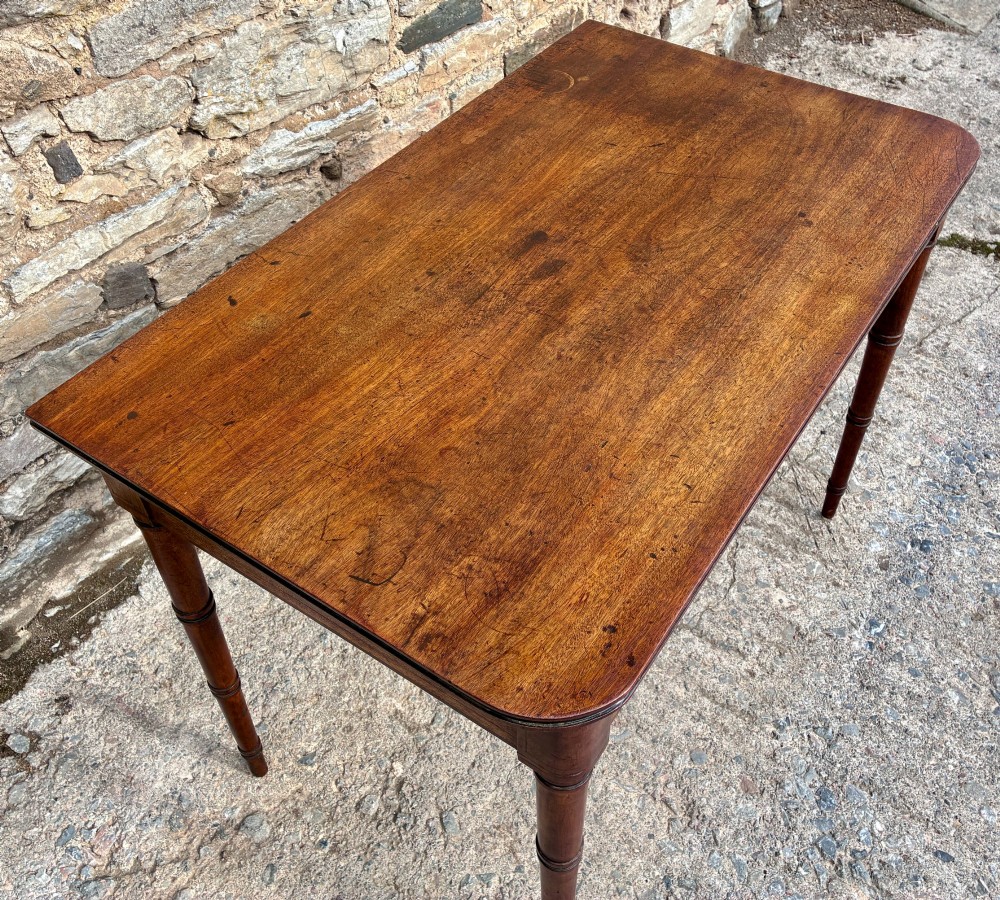 A rectangular Georgian mahogany side table featuring rounded top corners and four ring-turned tapered legs. View IV