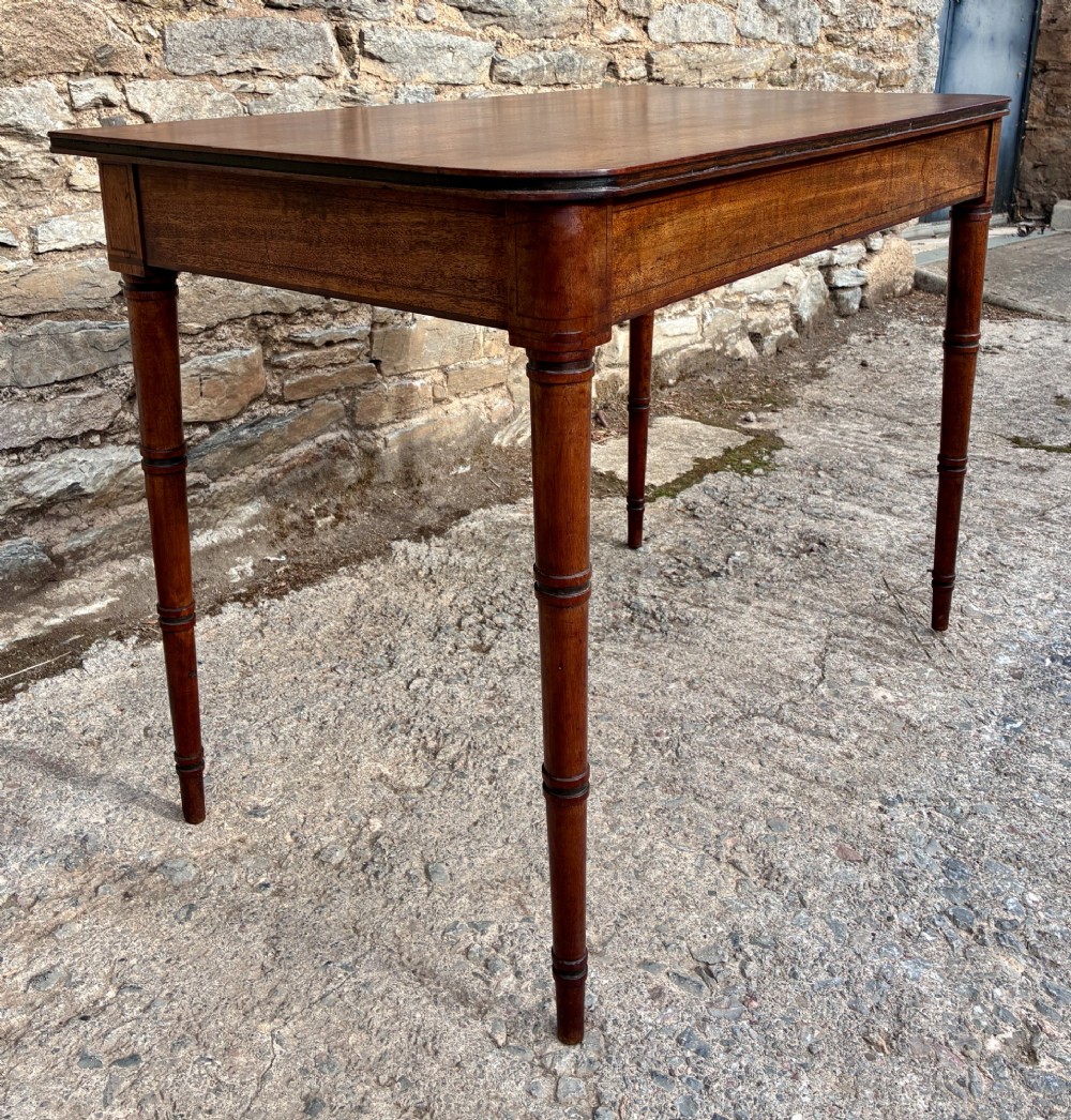 A rectangular Georgian mahogany side table featuring rounded top corners and four ring-turned tapered legs. View V