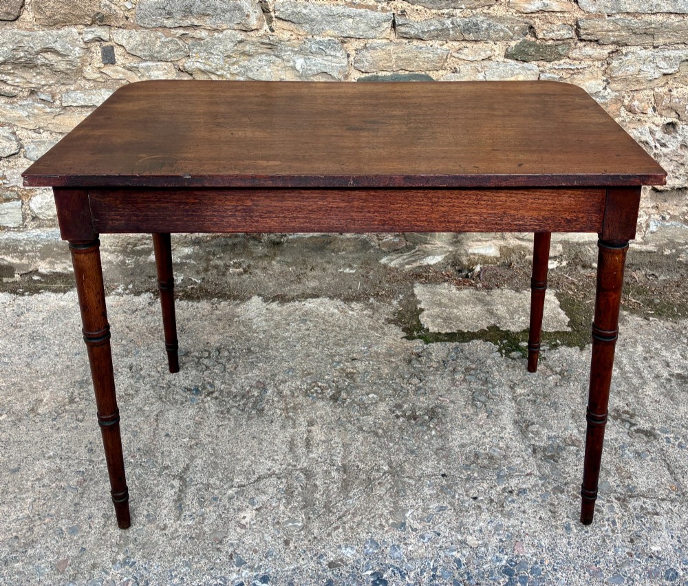 A rectangular Georgian mahogany side table featuring rounded top corners and four ring-turned tapered legs. View X