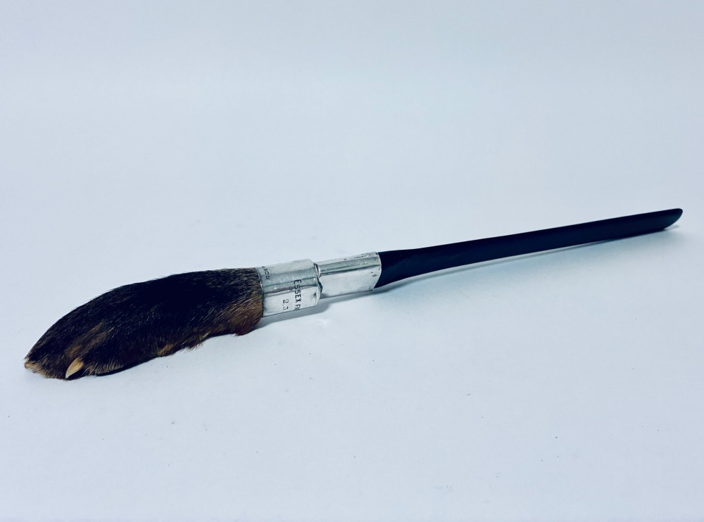 An antique page turner featuring a dark ebony blade connected via a silver collar to an otter paw handle. View II