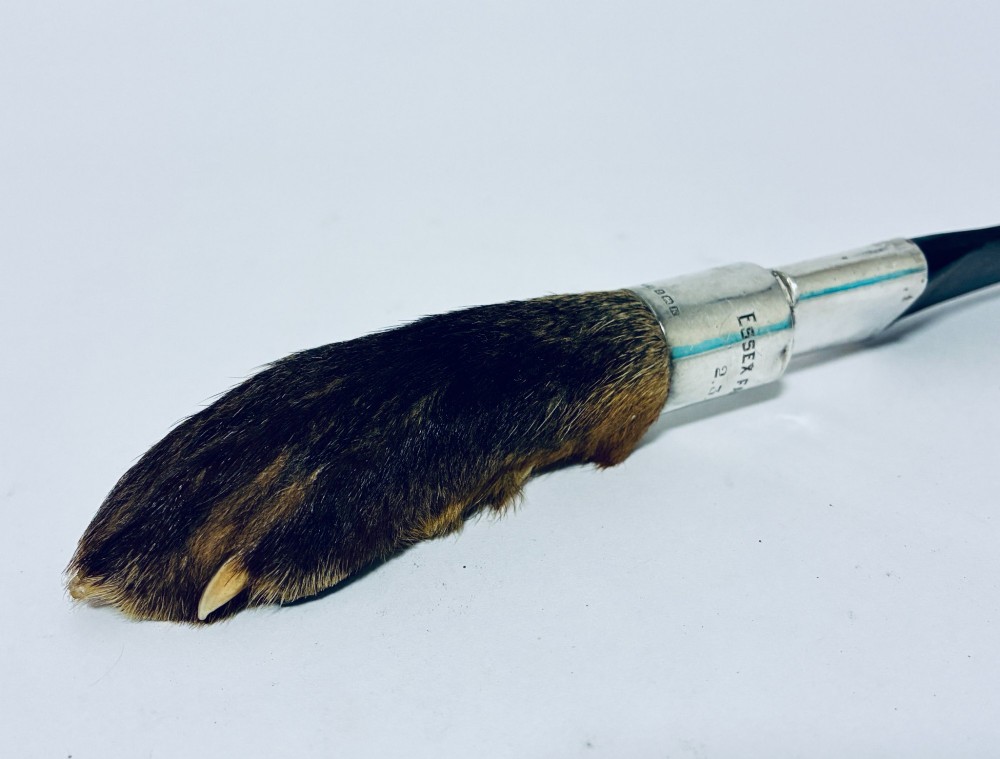An antique page turner featuring a dark ebony blade connected via a silver collar to an otter paw handle. View III