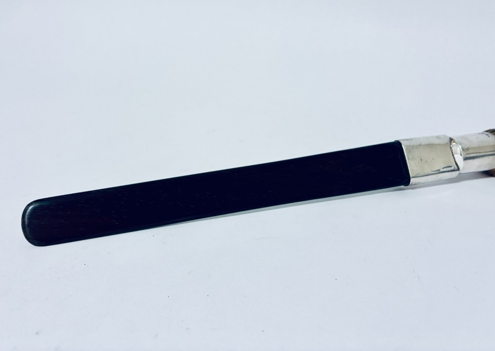 An antique page turner featuring a dark ebony blade connected via a silver collar to an otter paw handle. View VIII