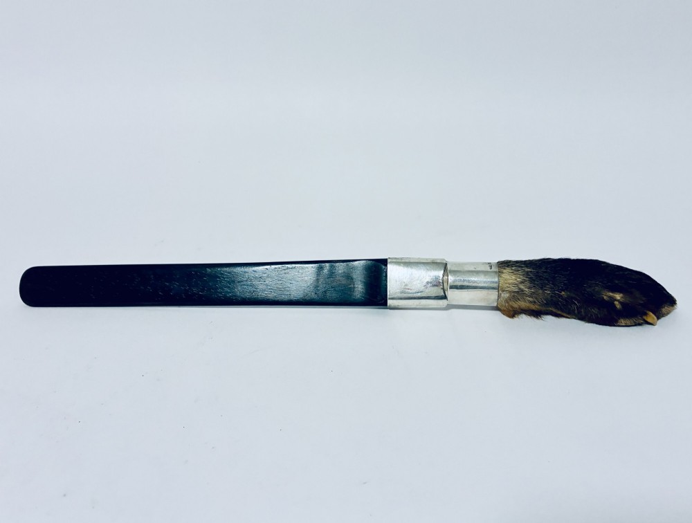 An antique page turner featuring a dark ebony blade connected via a silver collar to an otter paw handle. View IX