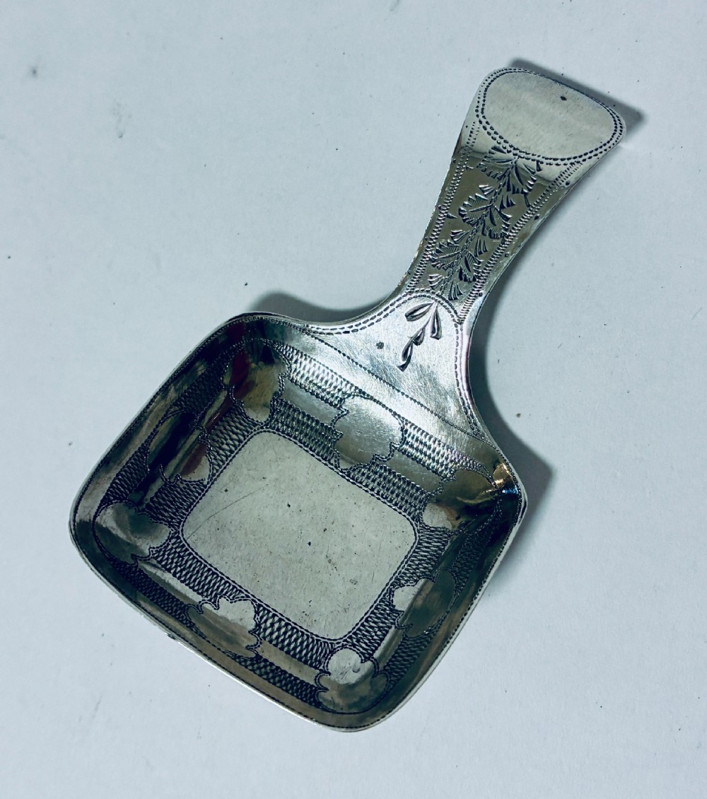 A Georgian sterling silver caddy spoon with a rectangular shovel-form bowl and bright-cut engraved geometric patterns on the handle. View II