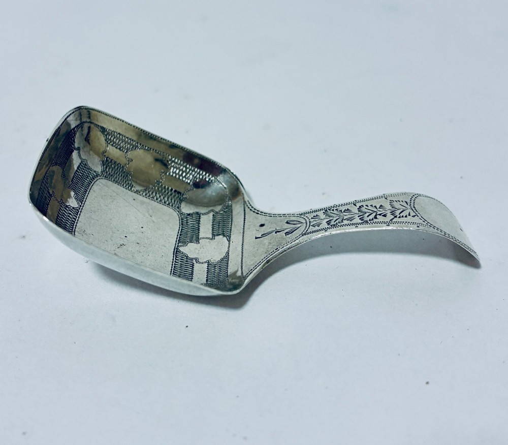 A Georgian sterling silver caddy spoon with a rectangular shovel-form bowl and bright-cut engraved geometric patterns on the handle. View III