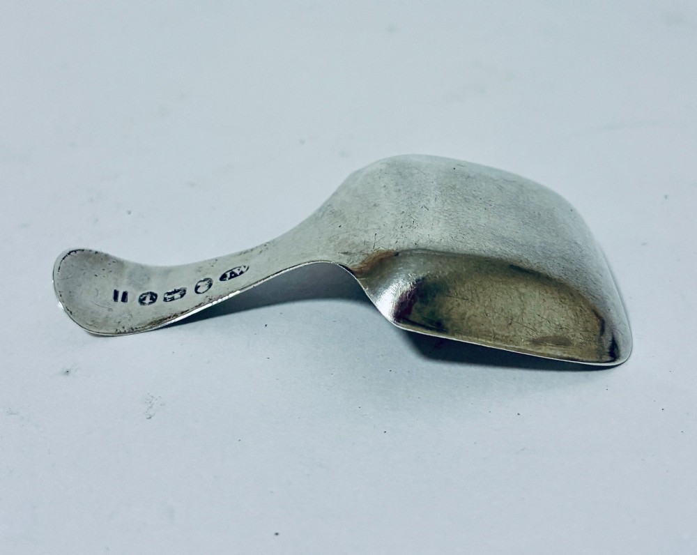 A Georgian sterling silver caddy spoon with a rectangular shovel-form bowl and bright-cut engraved geometric patterns on the handle. View VI
