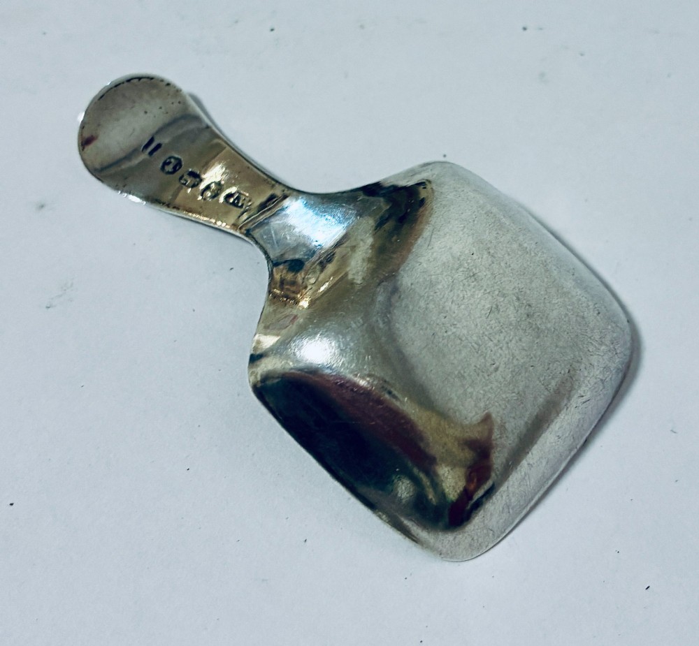 A Georgian sterling silver caddy spoon with a rectangular shovel-form bowl and bright-cut engraved geometric patterns on the handle. View VII