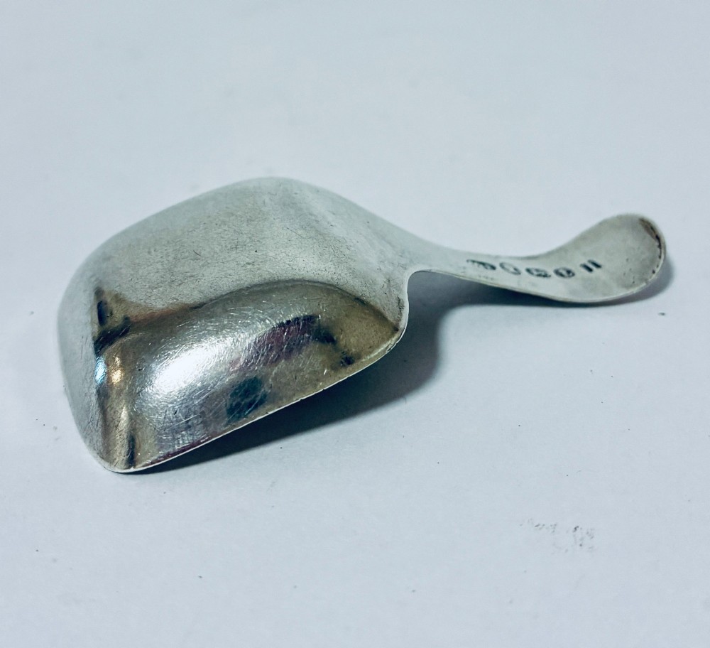 A Georgian sterling silver caddy spoon with a rectangular shovel-form bowl and bright-cut engraved geometric patterns on the handle. View IX