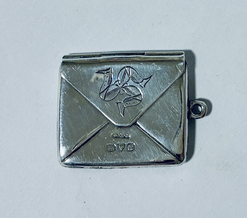 An envelope-shaped sterling silver stamp case featuring an engraved Isle of Man triskelion and clear hallmarks. View II