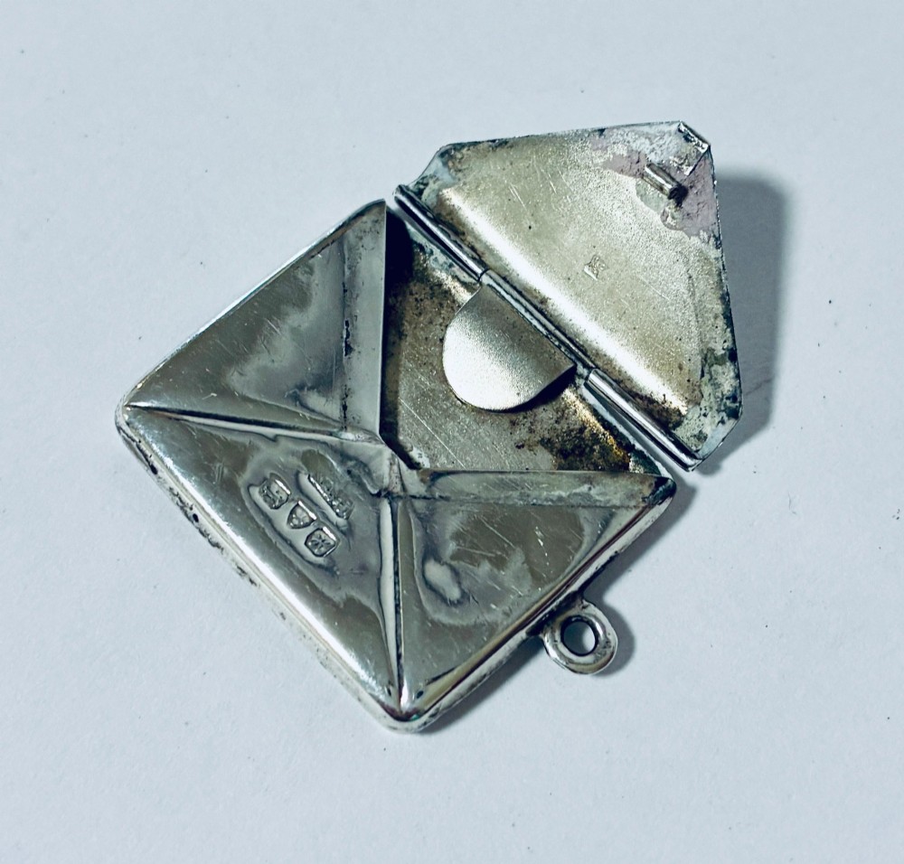 An envelope-shaped sterling silver stamp case featuring an engraved Isle of Man triskelion and clear hallmarks. View IV
