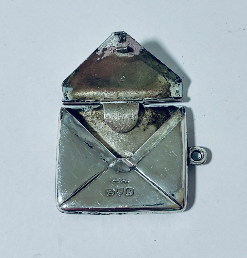 An envelope-shaped sterling silver stamp case featuring an engraved Isle of Man triskelion and clear hallmarks. View V