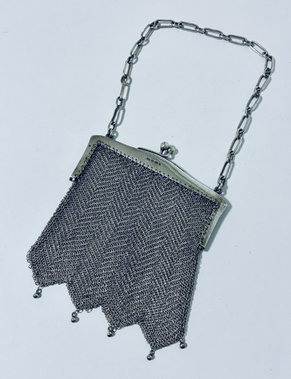 An Art Deco silver mesh purse featuring an engraved kiss-lock frame, a paperclip link chain handle, and a scalloped hem with drop-bead detailing. View V