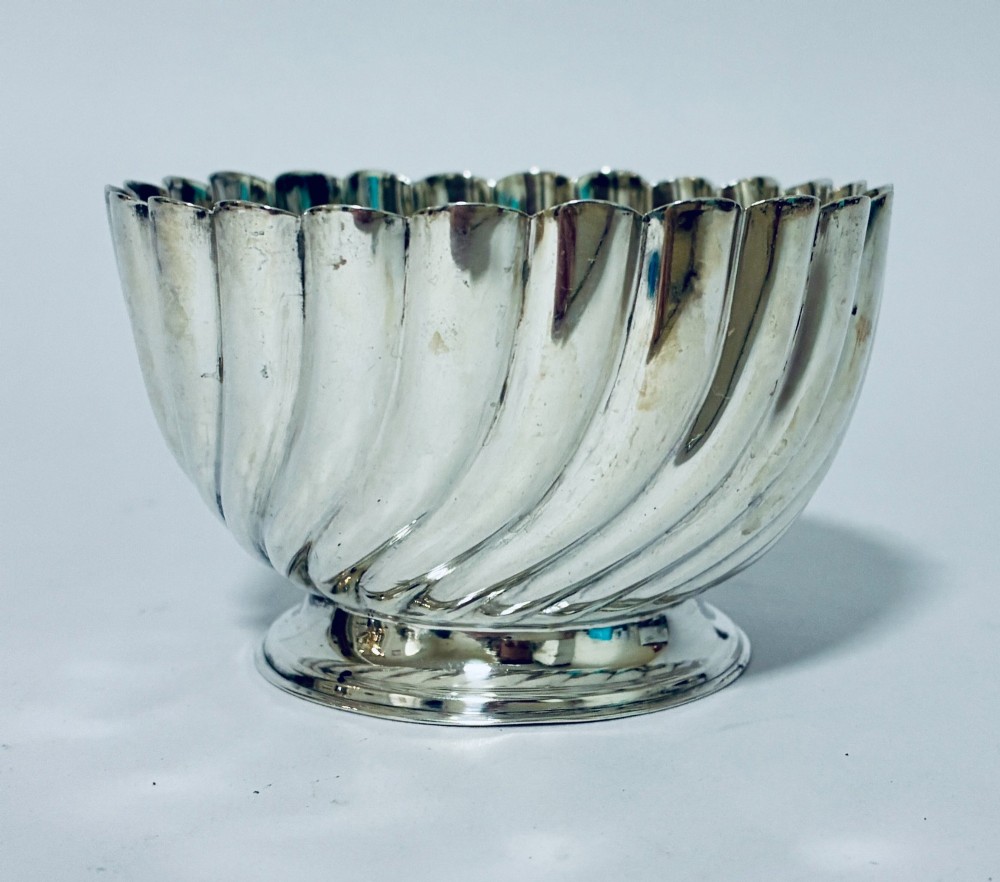 An antique silver pedestal bowl featuring spiralled fluted sides and a scalloped rim resting on a round moulded base. View III