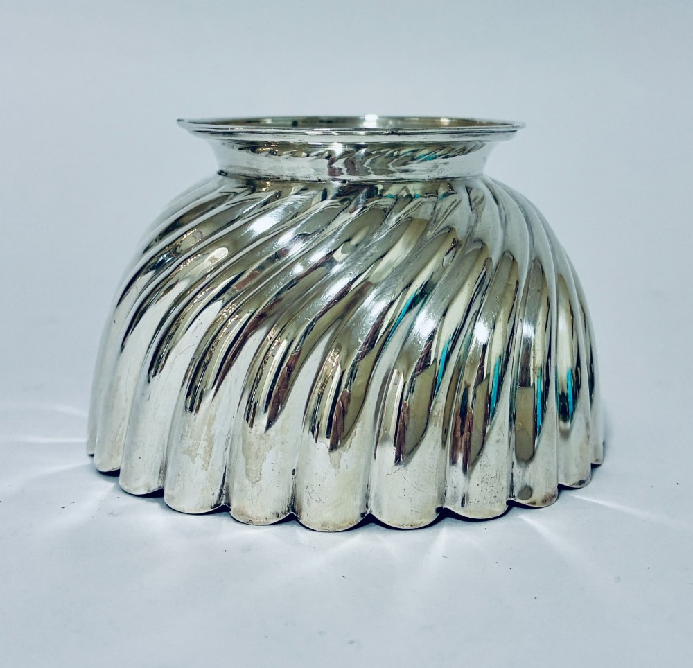 An antique silver pedestal bowl featuring spiralled fluted sides and a scalloped rim resting on a round moulded base. View IV