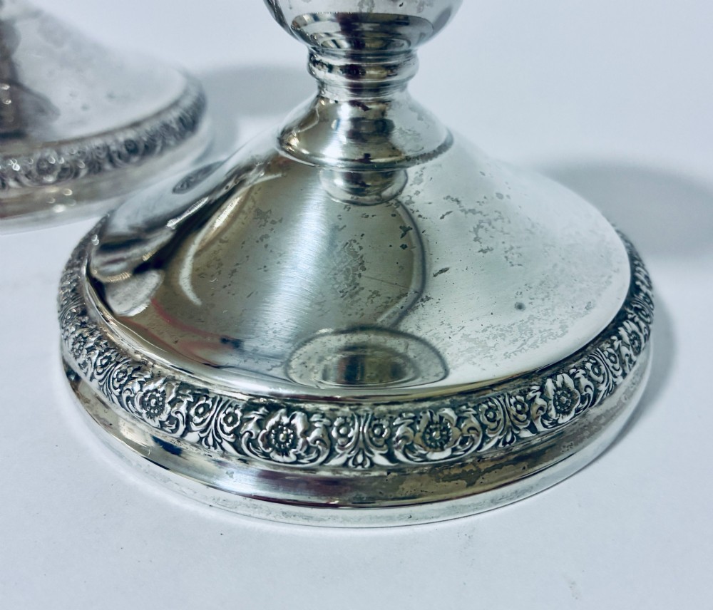 A pair of short sterling silver desk candlesticks featuring round bases with chased floral borders and baluster stems. View III