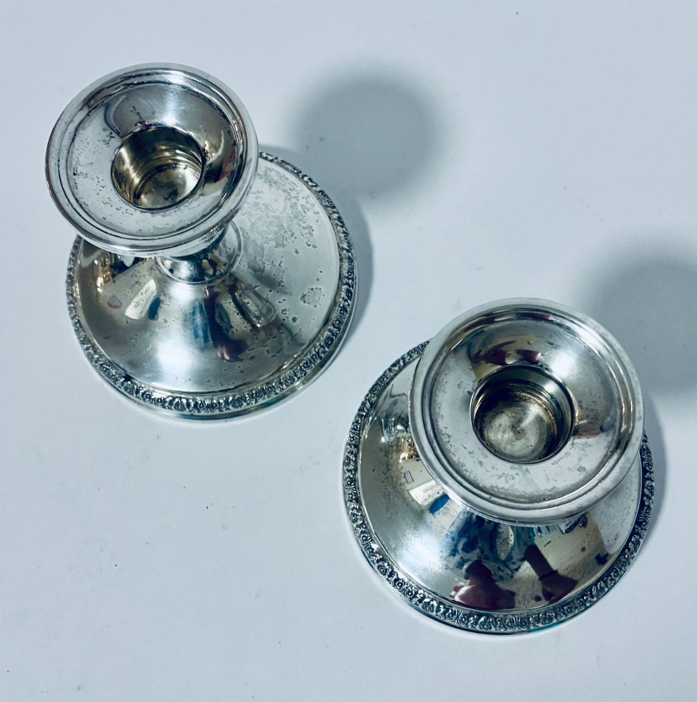 A pair of short sterling silver desk candlesticks featuring round bases with chased floral borders and baluster stems. View IV