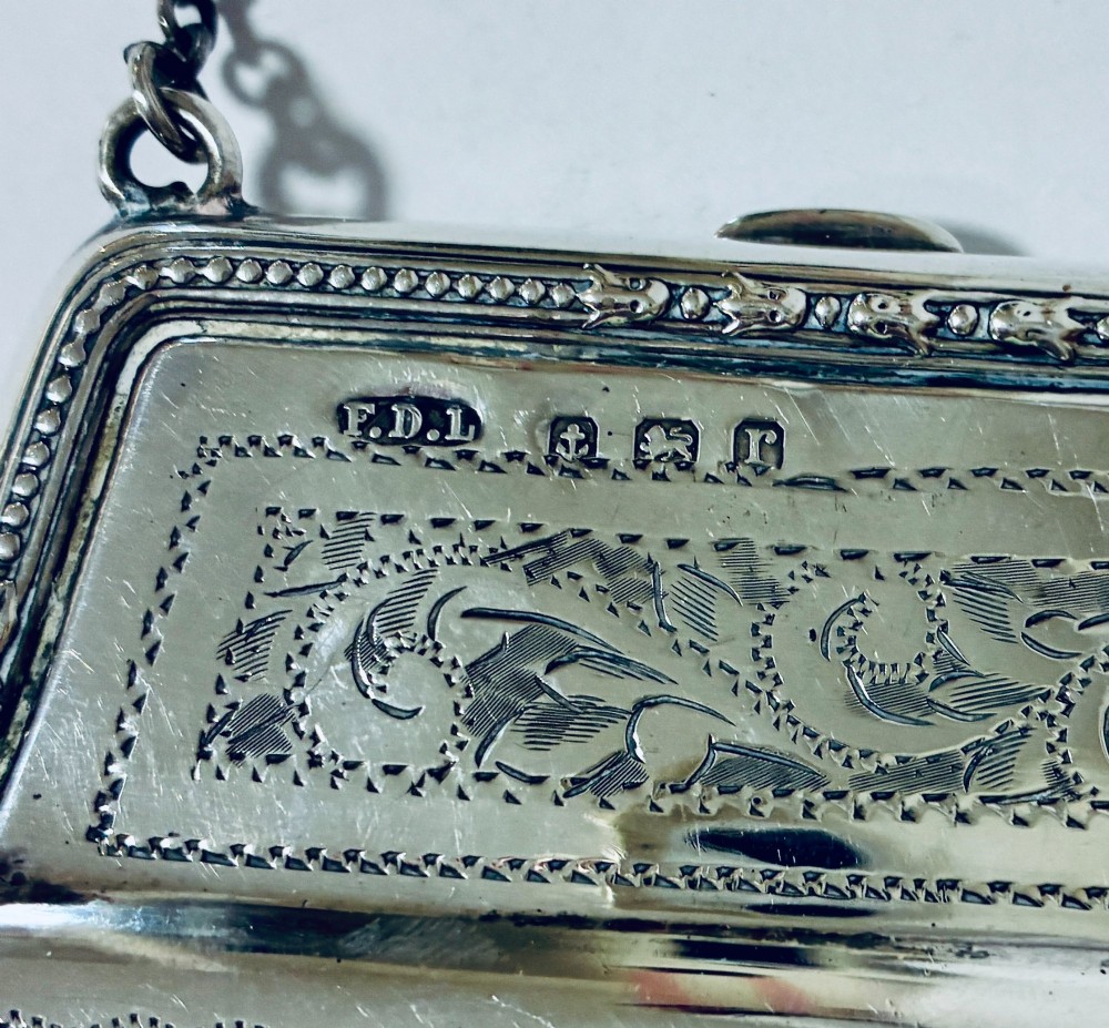 An antique sterling silver evening purse featuring engraved floral scrollwork, visible hallmarks along the upper frame, and a chain handle with a finger ring. View IV