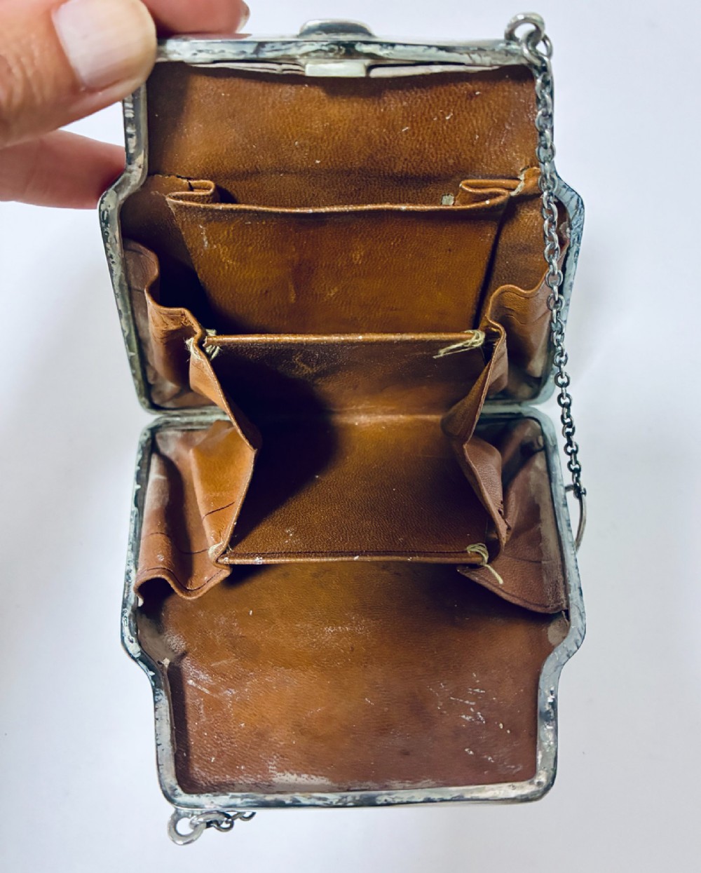 An antique sterling silver evening purse featuring engraved floral scrollwork, visible hallmarks along the upper frame, and a chain handle with a finger ring. View XII