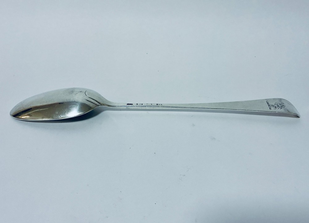 An 18th-century silver serving spoon featuring an elongated oval bowl and a smooth tapered handle. View V