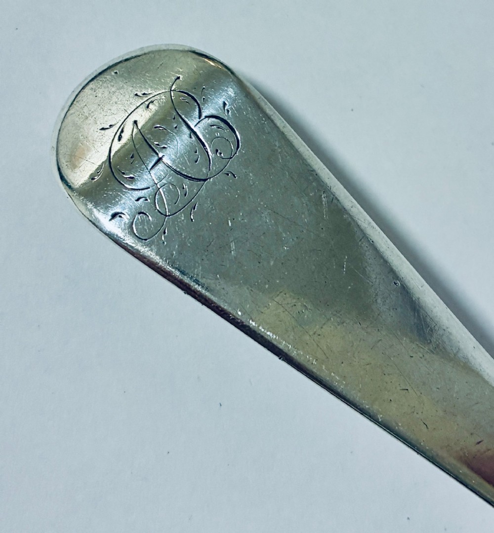 An antique sterling silver serving spoon featuring a tapered handle with monogram engraving and an oval bowl. View II