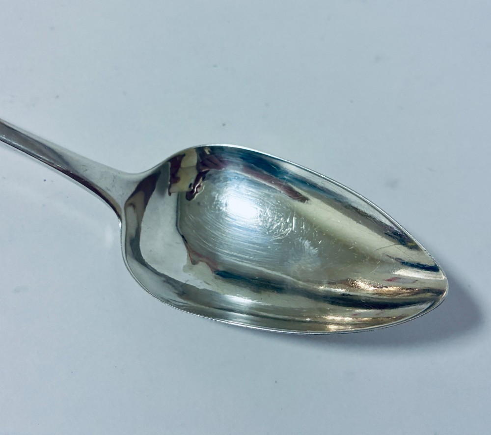 An antique sterling silver serving spoon featuring a tapered handle with monogram engraving and an oval bowl. View III