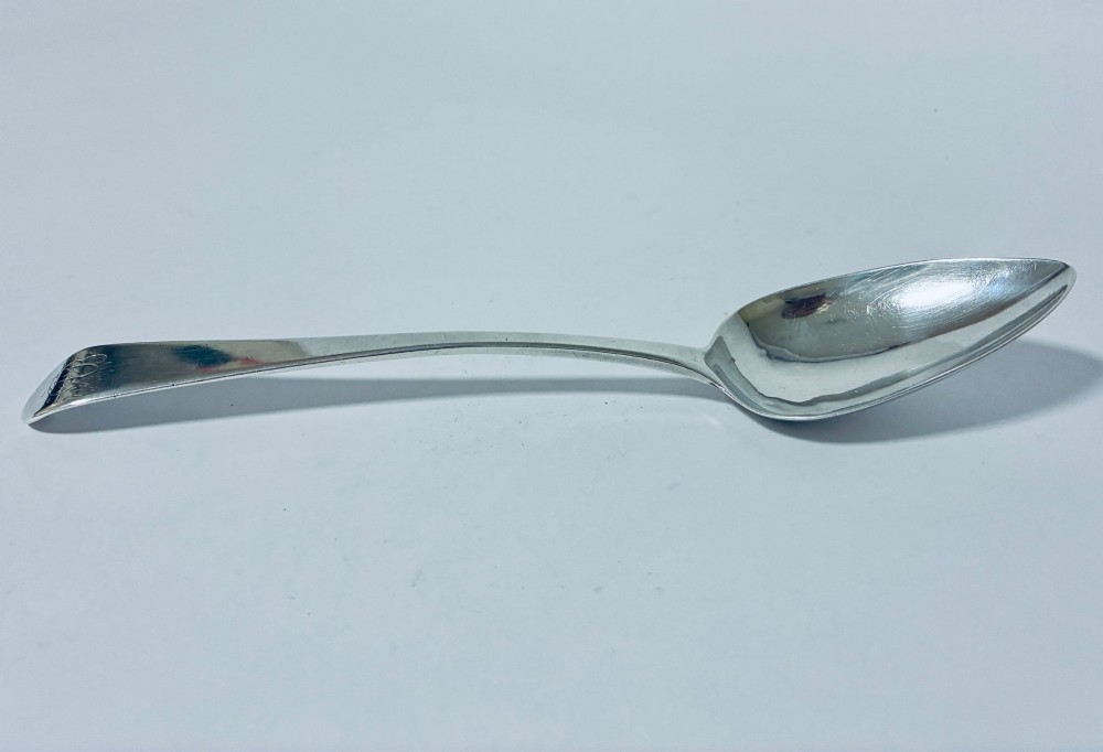 An antique sterling silver serving spoon featuring a tapered handle with monogram engraving and an oval bowl. View IV