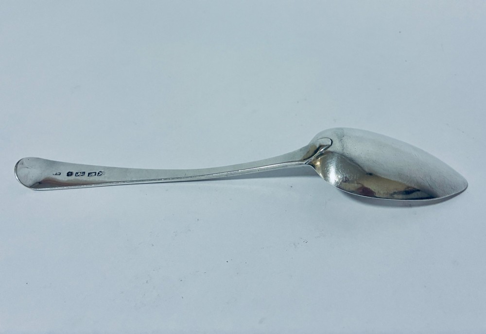An antique sterling silver serving spoon featuring a tapered handle with monogram engraving and an oval bowl. View V