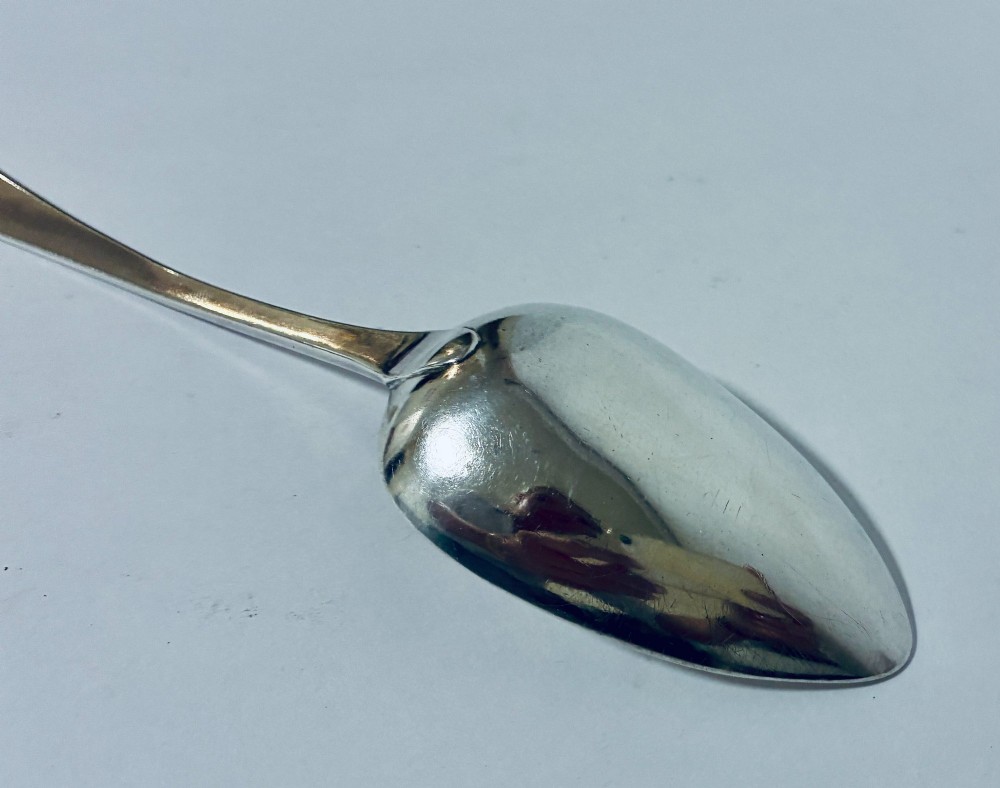 An antique sterling silver serving spoon featuring a tapered handle with monogram engraving and an oval bowl. View VI