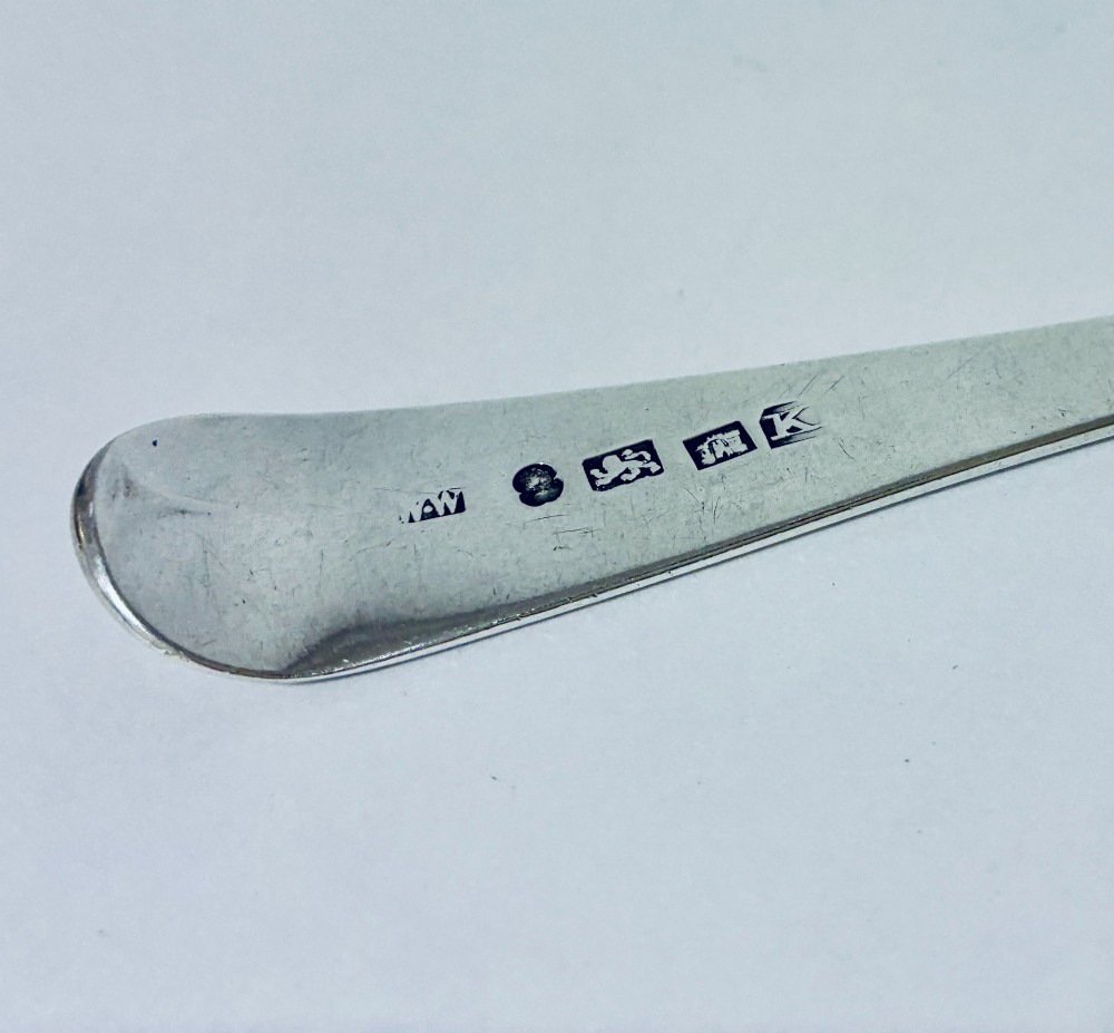 An antique sterling silver serving spoon featuring a tapered handle with monogram engraving and an oval bowl. View VII