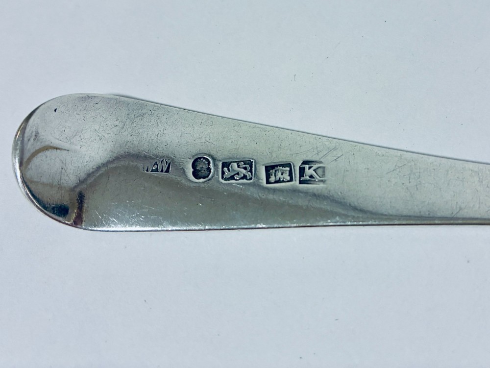 An antique sterling silver serving spoon featuring a tapered handle with monogram engraving and an oval bowl. View VIII