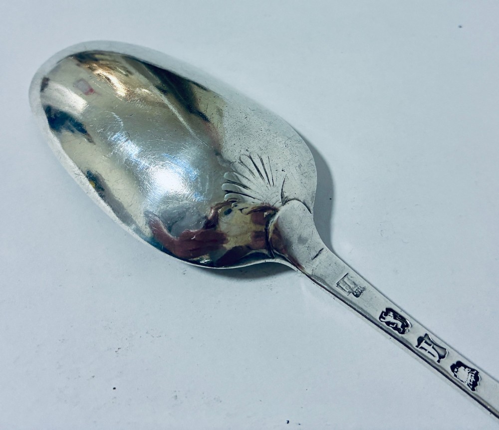 An 18th-century sterling silver serving spoon with a wide oval bowl and a smooth stem handle resting on a plain background. View VI